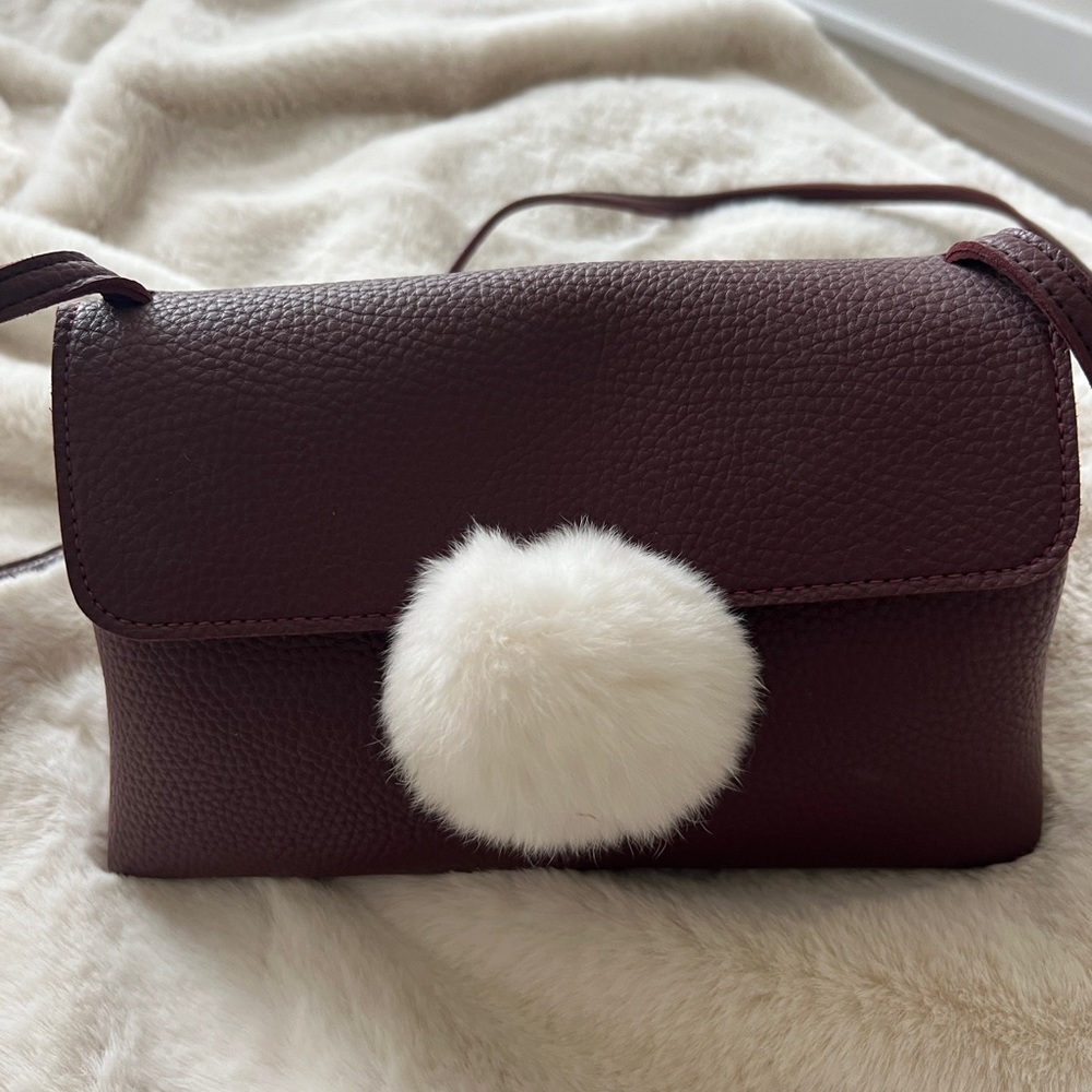 Maroon crossbody bag with white rabbit ball accent